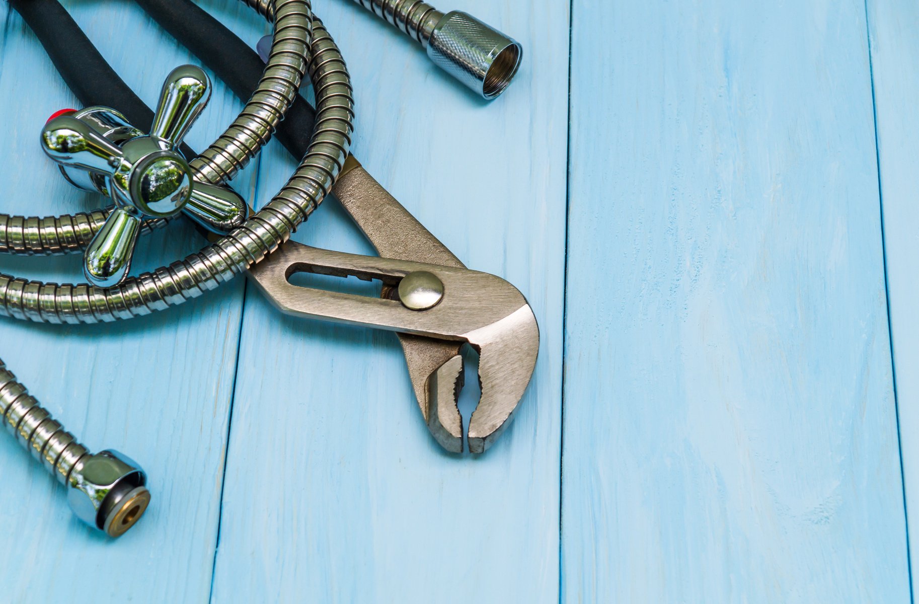 Plumbing tools and a hose on blue boards were prepared by a craftsman before repair